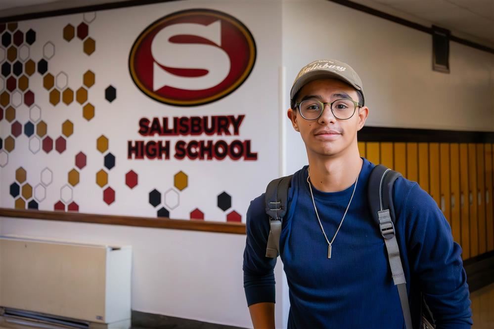 male student standing in hall in front of SHS mural